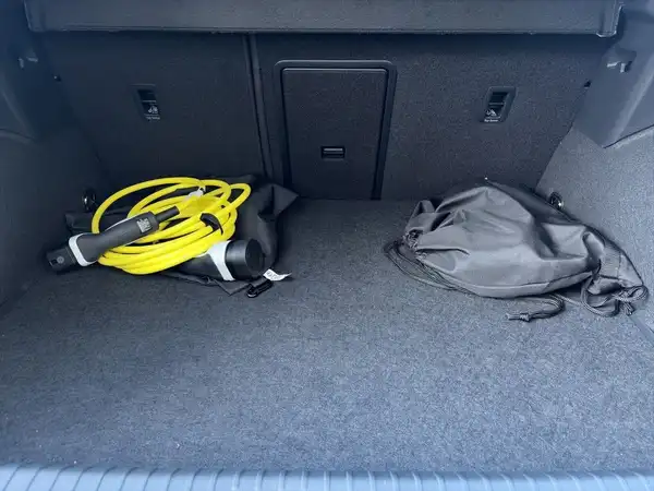 Das Bild zeigt den Kofferraum eines CUPRA FORMENTOR, mit schwarzem Interieur und Kabeln sowie Taschen im Kofferraum.
