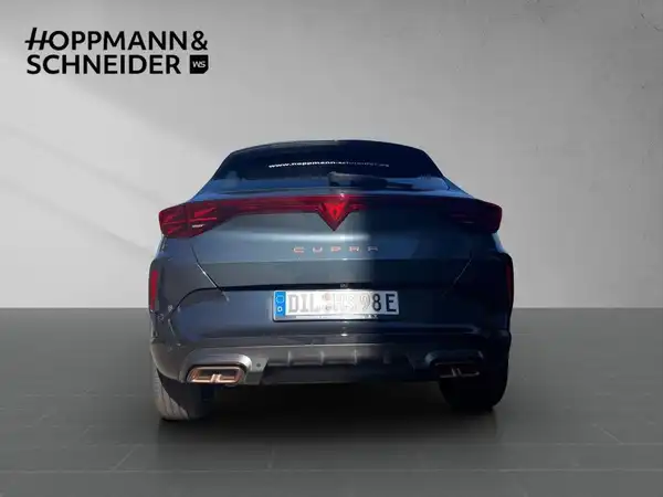 Das Bild zeigt die Rückansicht eines grauen CUPRA Formentor. Im Hintergrund ist das Händlerlogo von HOPPMANN & SCHNEIDER zu sehen.
