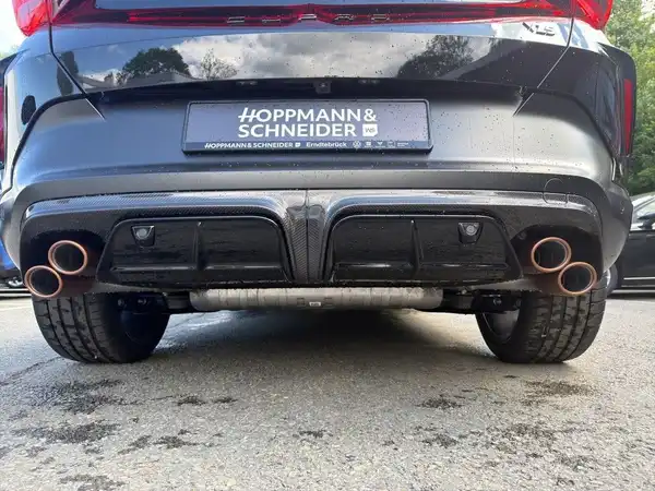 Das Bild zeigt die Rückansicht eines schwarzen Fahrzeugs, entweder einem CUPRA FORMENTOR oder ähnlichem Modell. Es sind sowohl die Auspuffanlagen als auch ein Händlerlogo sichtbar.