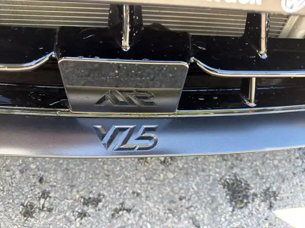 Das Bild zeigt die Frontansicht eines Fahrzeuges in Schwarz, insbesondere den Kühlergrill mit dem Emblem 'VL5'. Es ist keine Innenaufnahme und enthält kein Händlerlogo oder markante Texteinblendungen.