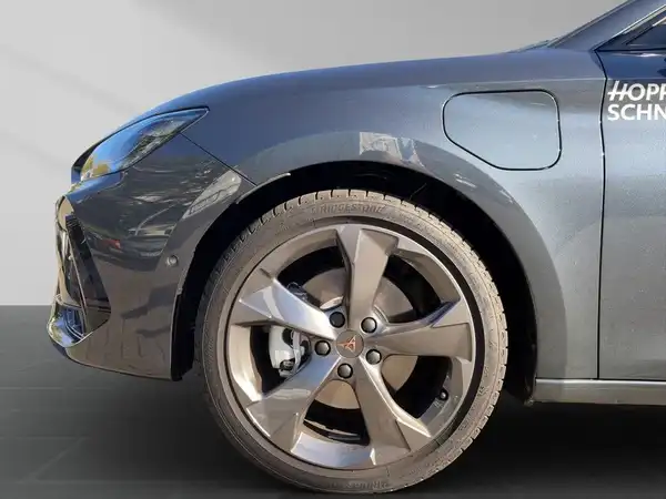 Das Bild zeigt eine Seitenaufnahme eines grauen CUPRA LEON SPORTSTOURER mit auffälligen Felgen. Es sind markante Texteinblendungen sichtbar.