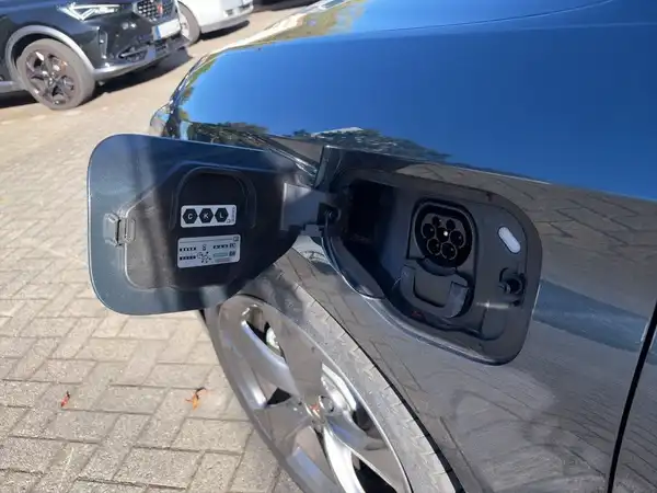 Das Bild zeigt die Ladeklappe eines schwarzen CUPRA Fahrzeuges von der Seite. Es handelt sich um eine Aufnahme, die den Ladeanschluss zeigt.