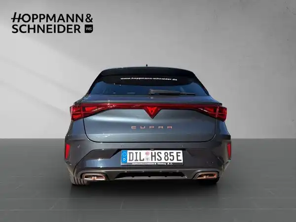 Das Bild zeigt den hinten aufgenommenen CUPRA LEON SPORTSTOURER in grau. Es enthält das Händlerinformationslogo.