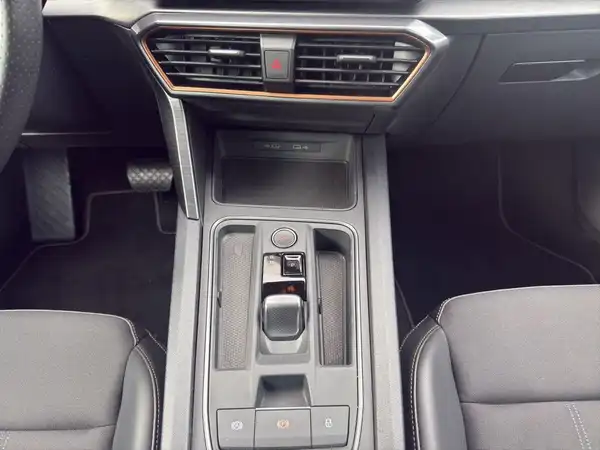 Das Bild zeigt den Innenraum eines Fahrzeugs, genauer gesagt die Mittelkonsole mit einem Fokus auf die Schaltflächen und den Gear Shifter, die Sitze sind schwarz.