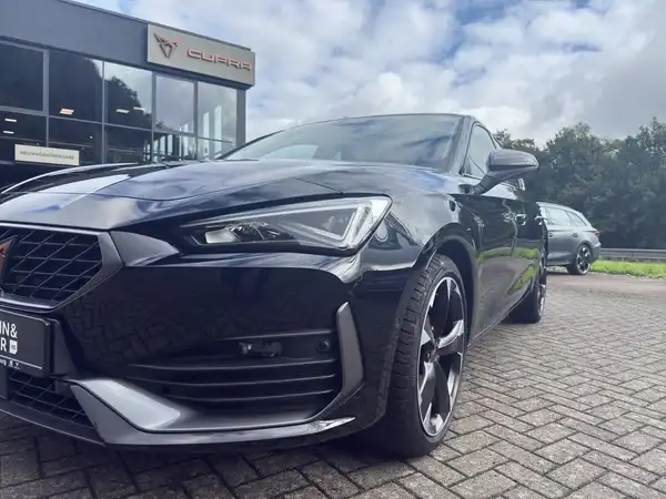 Das Bild zeigt einen CUPRA LEON in schwarz, aufgenommen von der Seite. Im Hintergrund ist das Händlerlogo sichtbar.