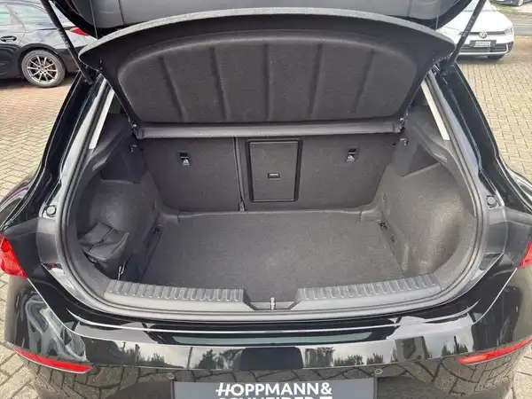 Das Bild zeigt den Kofferraum eines schwarzen Fahrzeugs, aufgenommen von hinten. Im Bild ist das Händlerlogo 'HOPPMANN&' sichtbar.