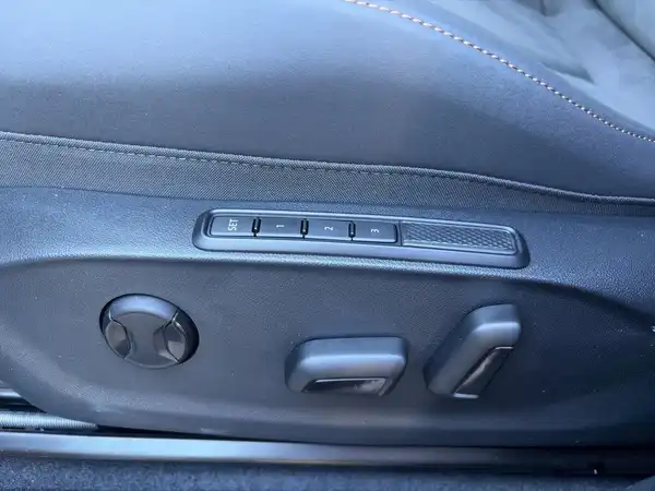 Das Bild zeigt die Innenaufnahme des Fahrzeugs, speziell eine Detailansicht des Sitzverstellmechanismus auf der Fahrerseite. Die Innenfarbe ist schwarz.