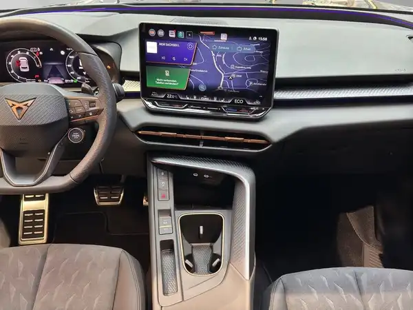Das Bild zeigt das Interieur eines CUPRA TERRAMAR aus der Innenansicht. Das Fahrzeug hat eine schwarze Innenausstattung mit einem Muster auf den Sitzen. Außerdem sind markante Texteinblendungen auf dem Bildschirm sichtbar.
