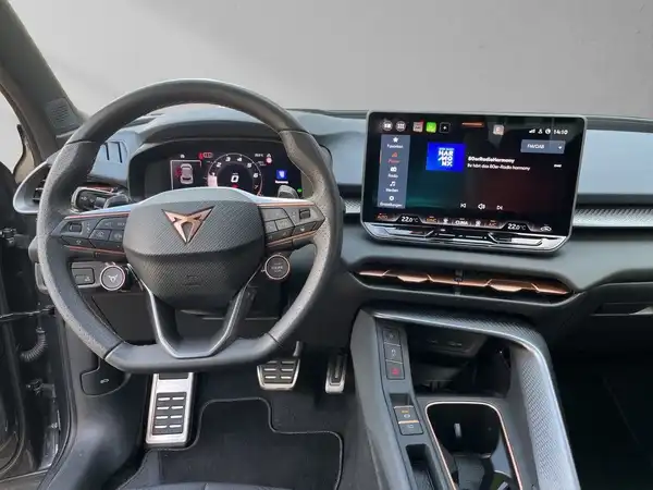 Das Bild zeigt das Interieur eines CUPRA TERRAMAR von der Fahrerseite, in schwarz mit einem modernen Touchscreen und einem sportlichen Lenkrad.
