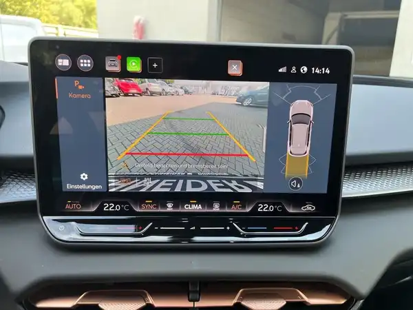 Aufnahme des Innenraums des Fahrzeugs, zeigt ein Navigations- und Rückfahrkamera-Display mit markanten Texteinblendungen.