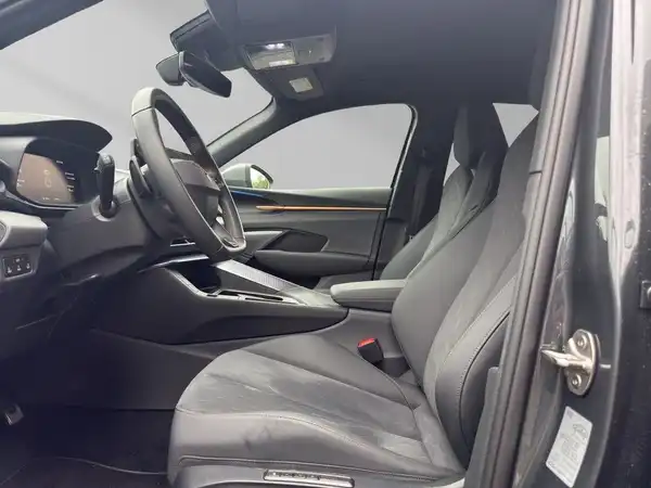 Innenaufnahme eines Fahrzeugs in Schwarz mit dunkelorangenen Akzenten, das Vorderteil mit dem Lenkrad und dem Fahrersitz ist sichtbar.