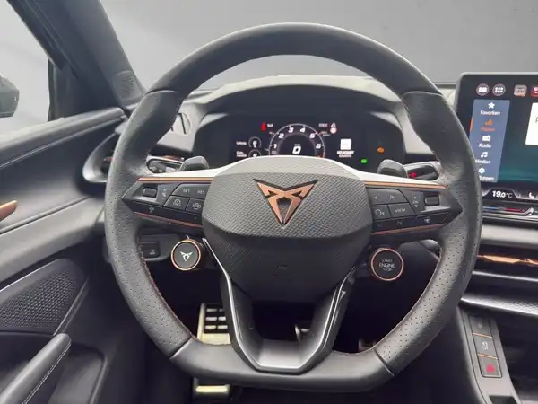 Das Bild zeigt das Interieur eines CUPRA TERRAMAR aus der Sicht des Fahrers, mit einem schwarzen Lenkrad und Bronzetönen.