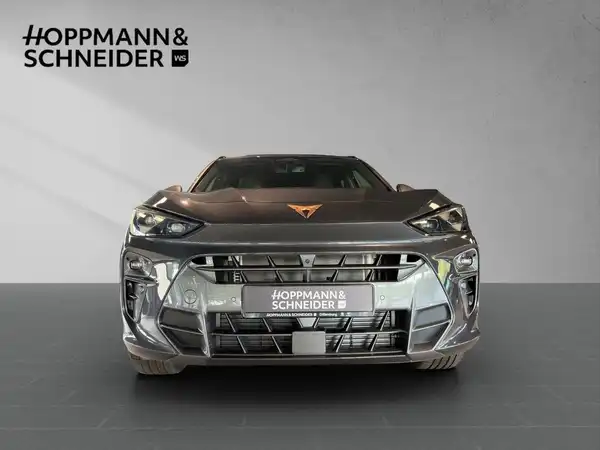 Das Bild zeigt ein graues Fahrzeug (CUPRA TERRAMAR) aus der Frontalansicht. Im Hintergrund sind die Logos und der Schriftzug des Händlers HOPPMANN & SCHNEIDER zu sehen.