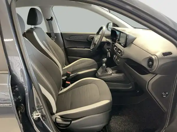 Das Bild zeigt das Innere eines Hyundai i10 mit grauen und schwarzen Sitzen, die Fahrer- und Beifahrerplätze sichtbar sind.