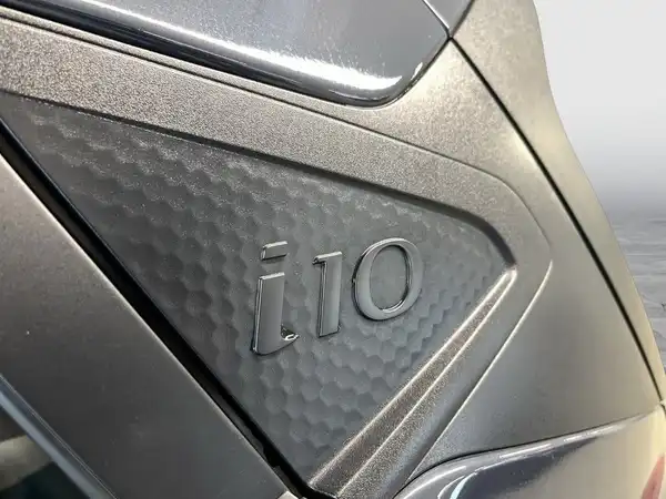Das Bild zeigt einen grauen Hyundai i10 aus der Seitenansicht, wobei das Emblem gut sichtbar ist.