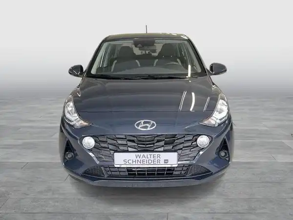 Das Bild zeigt einen grauen HYUNDAI I10 aus der Frontansicht. Auf dem Bild ist das Händlerlogo mit dem Namen 'WALTER SCHNEIDER' zu sehen.
