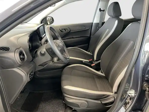 Das Bild zeigt das Innere eines HYUNDAI I10 von der Seite, mit einem schwarz-grauen Interieur und einer modernen Ausstattung.