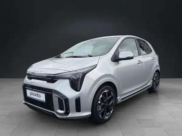 Das Bild zeigt einen silbernen KIA Picanto von der Seite, es enthält ein Händlerlogo und einige markante Texteinblendungen.