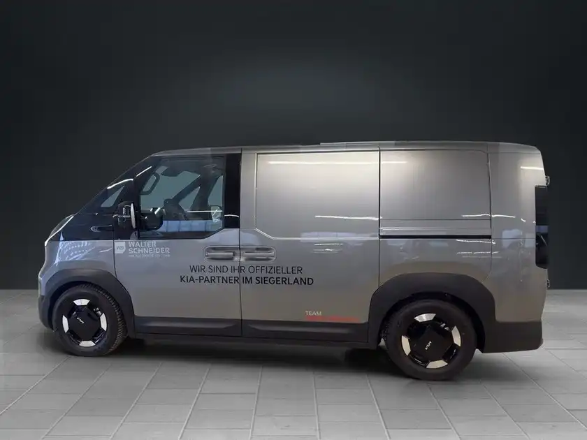 Das Bild zeigt ein graues Fahrzeug (KIA PV5) aus der Seitenansicht. Es enthält das Händlerlogo und markante Texteinblendungen.