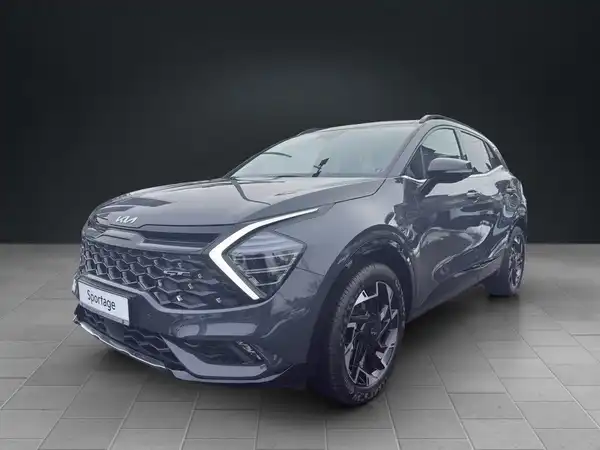 Das Bild zeigt einen grauen KIA Sportage aus der Frontansicht, mit markanten Texteinblendungen.