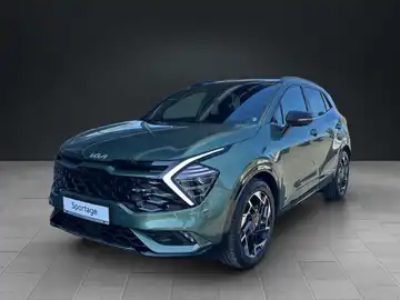 Das Bild zeigt einen KIA Sportage von vorne in grüner Farbe. Das Händlerlogo ist deutlich sichtbar und es gibt markante Texteinblendungen.