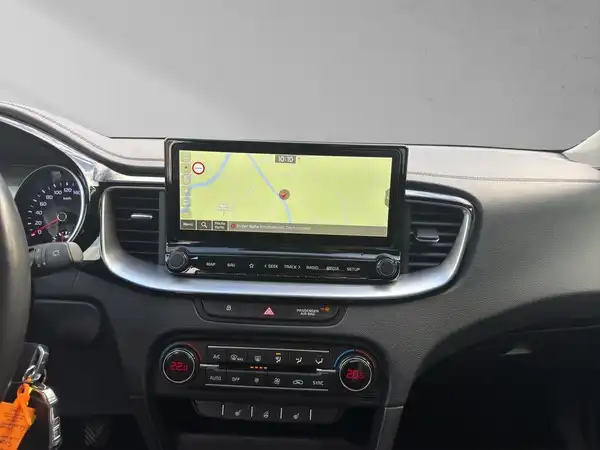 Das Bild zeigt das Innere eines Fahrzeugs, konkret das Armaturenbrett mit einem Navigationsgerät und verschiedenen Bedienelementen. Die Innenfarbe ist schwarz.
