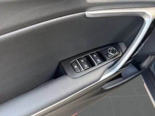 Das Bild zeigt die Innenseite der Tür eines Fahrzeugs mit einem schwarzen Innenraum und Steuerungselementen für Fensterheber. Es handelt sich um eine Innenaufnahme des Fahrzeugs.