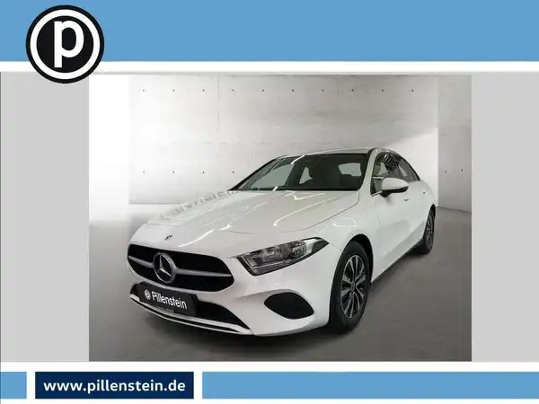 Das Bild zeigt einen weißen Mercedes-Benz A 180 d aus der Frontalansicht, mit dem Händlerlogo eingeblendet.