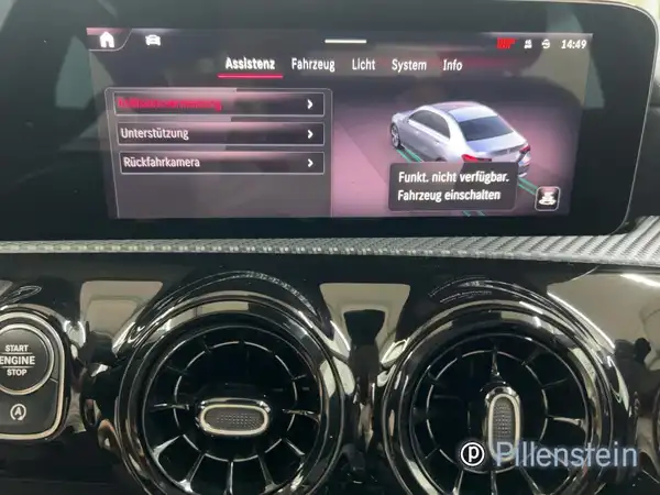 Das Bild zeigt das Interieur eines Mercedes-Benz A 180 d mit schwarzem Interieur und einem Bildschirm, auf dem verschiedene Assistenzsysteme angezeigt werden.
