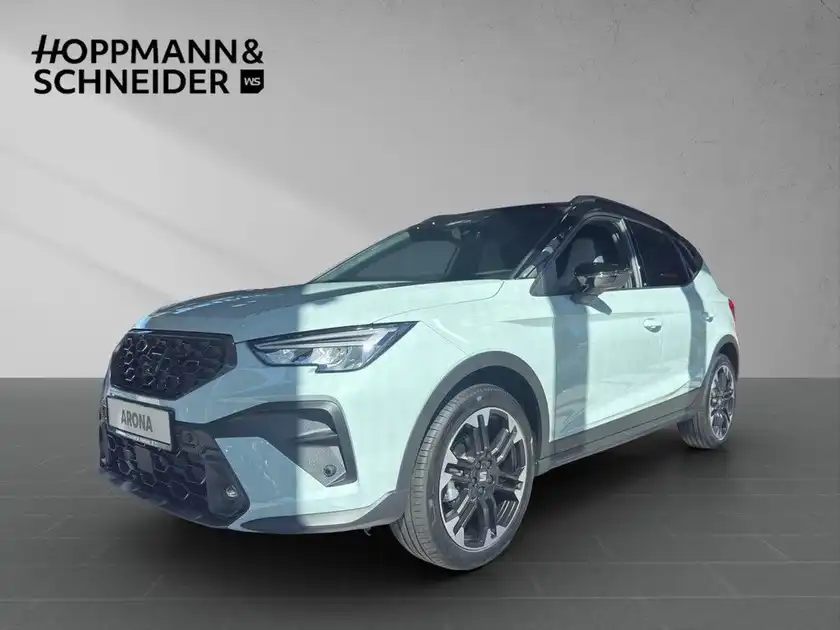 Das Bild zeigt einen SEAT ARONA aus der Seitenansicht in weißer Farbe mit dem Händlerlogo oben links und weiteren Texteinblendungen.