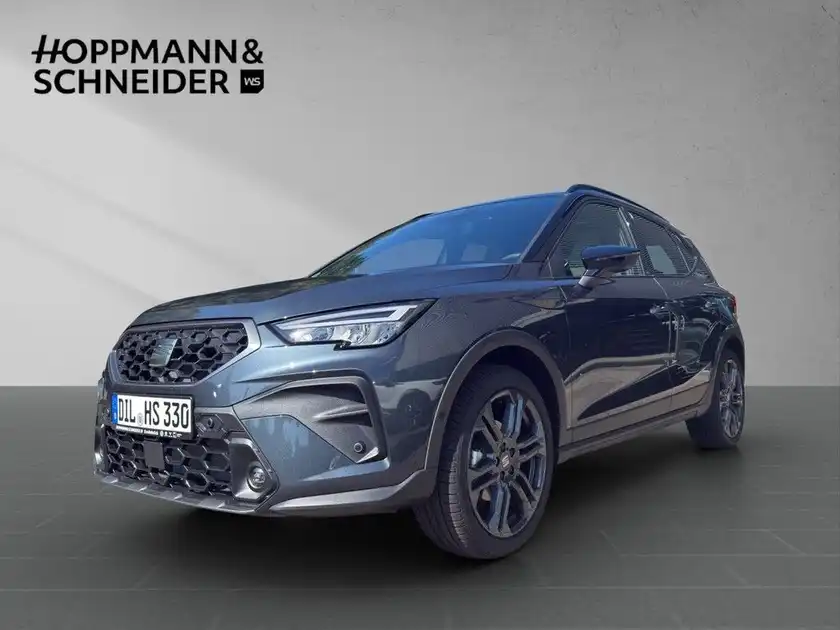 Das Bild zeigt einen SEAT ARONA in grauer Farbe, aufgenommen von der Seite. Im Hintergrund ist das Händlerlogo "HOPPMANN & SCHNEIDER" eingeblendet.