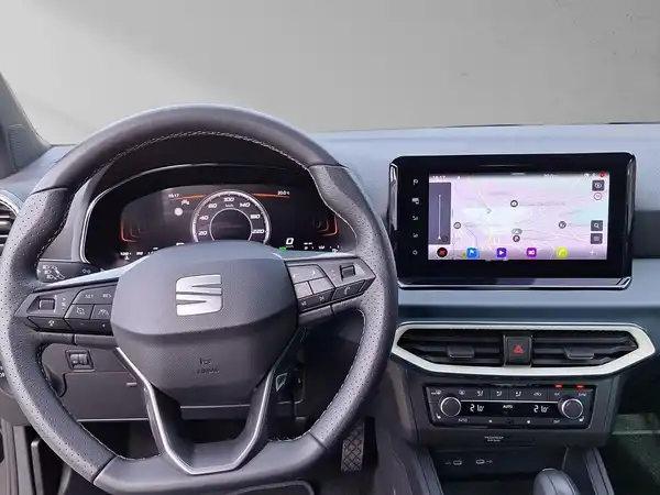 Das Bild zeigt das Innere eines SEAT ARONA, hauptsächlich den Lenker und das Infotainment-System. Die Innenausstattung ist schwarz.