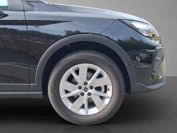 Das Bild zeigt die seitliche Ansicht eines schwarzen SEAT ARONA mit einer guten Sicht auf das Rad und die Karosserie.