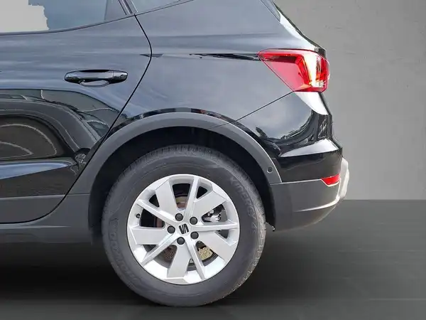 Das Bild zeigt die linke Seite eines schwarzen SEAT Arona mit einer Seitenaufnahme.