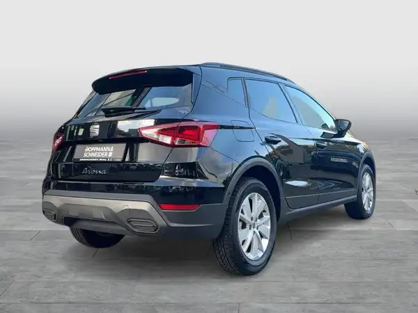 Das Bild zeigt einen schwarzen SEAT Arona von hinten, mit einem Händlerlogo.