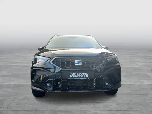 Das Bild zeigt einen schwarzen SEAT ARONA von vorne, mit einem Händlerlogo im Vordergrund.