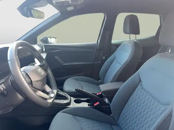 Das Bild zeigt den Innenraum eines Fahrzeugs, der in Grautönen gehalten ist, mit strukturierten Sitzen und einem modernen Armaturenbrett.