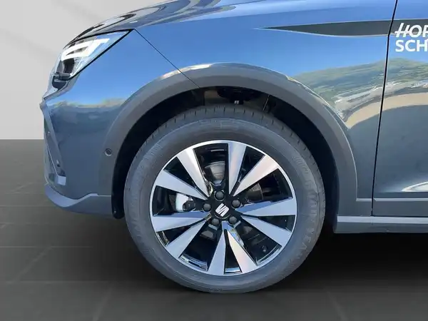Das Bild zeigt die Seite eines grauen SEAT ARONA mit einem sichtbaren Händlerinformationstext.