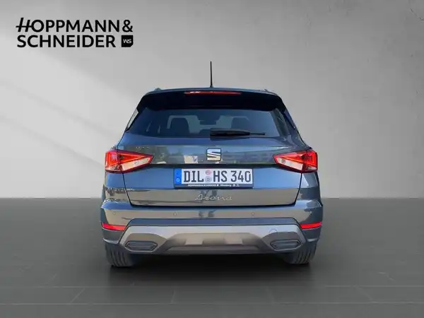 Das Bild zeigt das Fahrzeug, einen SEAT ARONA, von hinten in grauer Farbe. Im Hintergrund ist das Händlerlogo "HOPPMANN & SCHNEIDER" sichtbar.
