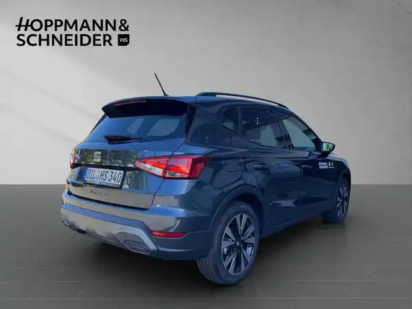 Das Foto zeigt ein blaues Fahrzeug (SEAT ARONA) von hinten. Es enthält das Händlerlogo und markante Texteinblendungen.