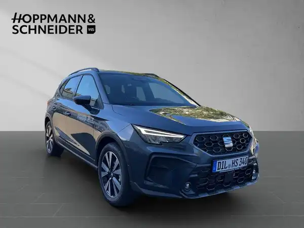 Das Bild zeigt einen SEAT ARONA von vorne, in der Farbe schwarz. Es handelt sich um ein Fahrzeugbild, auf dem das Händlerlogo von Hoppmann & Schneider zu sehen ist.