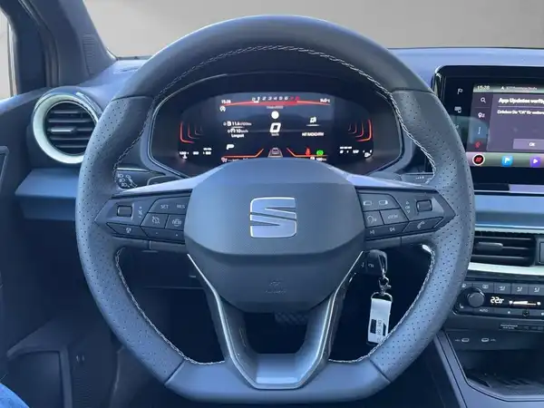 Das Bild zeigt das Innere eines SEAT Arona, insbesondere das Lenkrad und das Armaturenbrett. Das Interieur ist in Schwarz gehalten.