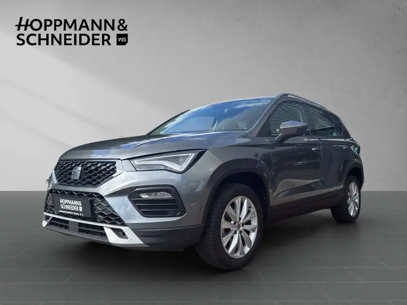 Das Bild zeigt einen grauen SEAT ATECA von der Seite, mit einem Händlerinformationslogo im oberen Bereich des Bildes.
