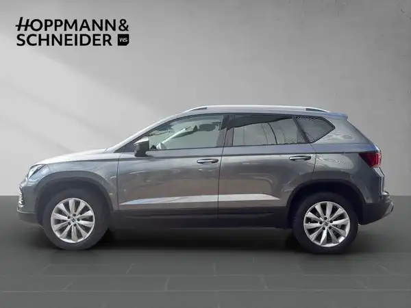 Das Bild zeigt einen seitlichen Blick auf einen grauen SEAT ATECA, mit dem Händlerlogo 'HOPPMANN & SCHNEIDER' im oberen Bereich.
