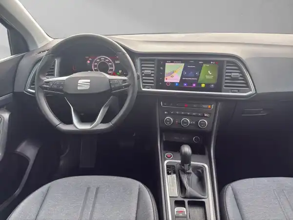 Das Bild zeigt das Innere eines SEAT Ateca aus der Perspektive des Fahrers, mit einem grauen Interieur und einem digitalen Bildschirm.