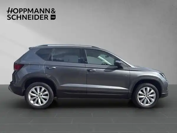 Das Bild zeigt einen grauen SEAT ATECA von der Seite. Das Händlersymbol von HOPPMANN & SCHNEIDER ist im Bild eingeblendet.