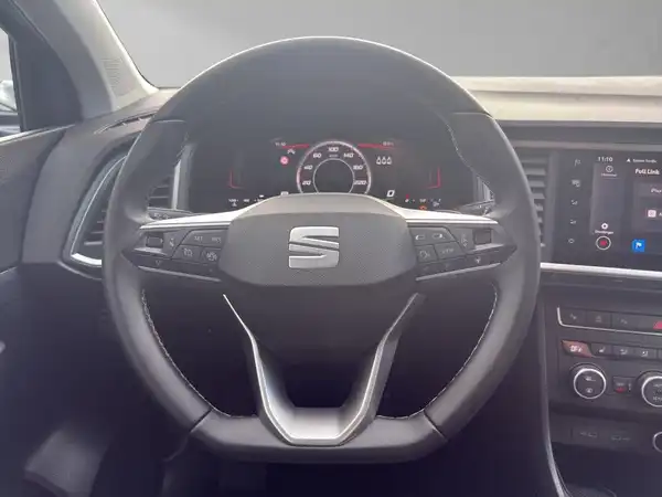 Das Bild zeigt den Innenraum eines SEAT Ateca mit einem schwarzen Lenkrad und Armaturenbrett.