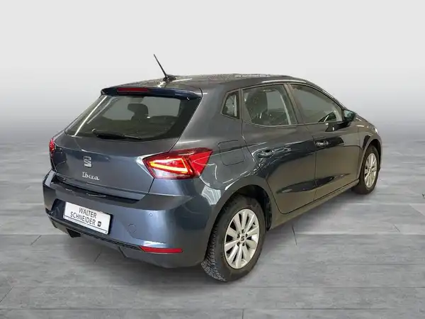 Das Bild zeigt einen blauen SEAT IBIZA von hinten. Es enthält das Händlerlogo und einige markante Texteinblendungen.