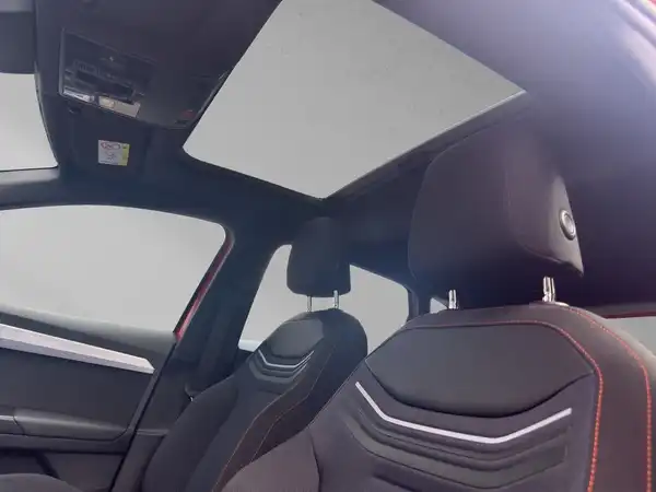 Das Bild zeigt den Innenraum eines SEAT Ibiza, aufgenommen von der Innenseite. Die Sitze sind schwarz mit roten Akzenten und es ist ein Panorama-Dach sichtbar.