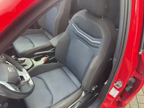 Das Bild zeigt den Innenraum eines roten SEAT IBIZA mit blauen und schwarzen Sitzen.